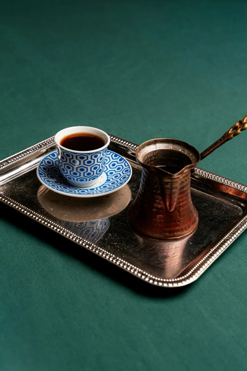 Dark coffee and a copper pot on a silver tray