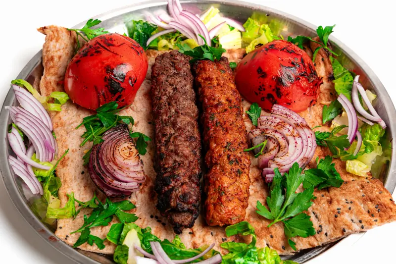 Two kabobs over flatbread in a metal tray