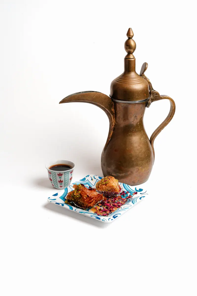 A brass dallah with coffee and baklava