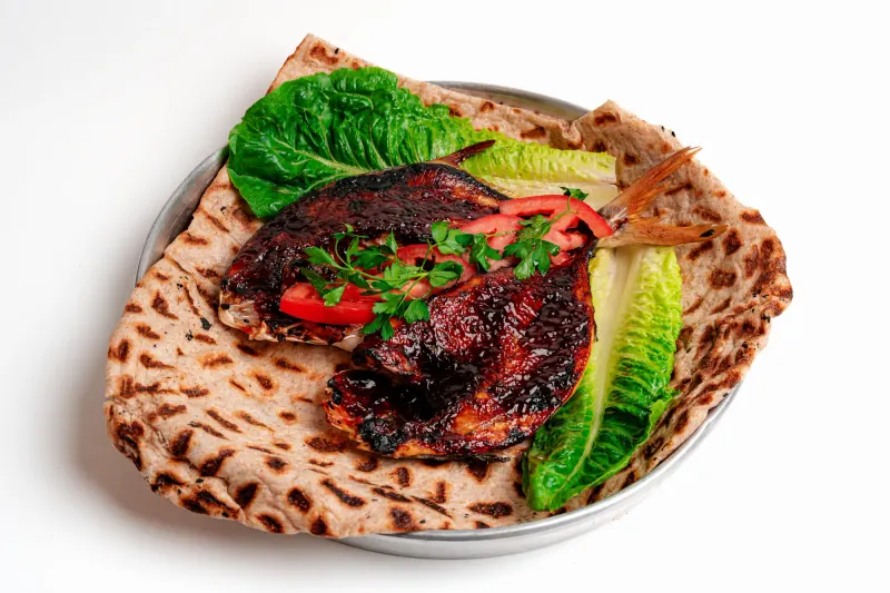 Baked fish over flatbread in a metal tray