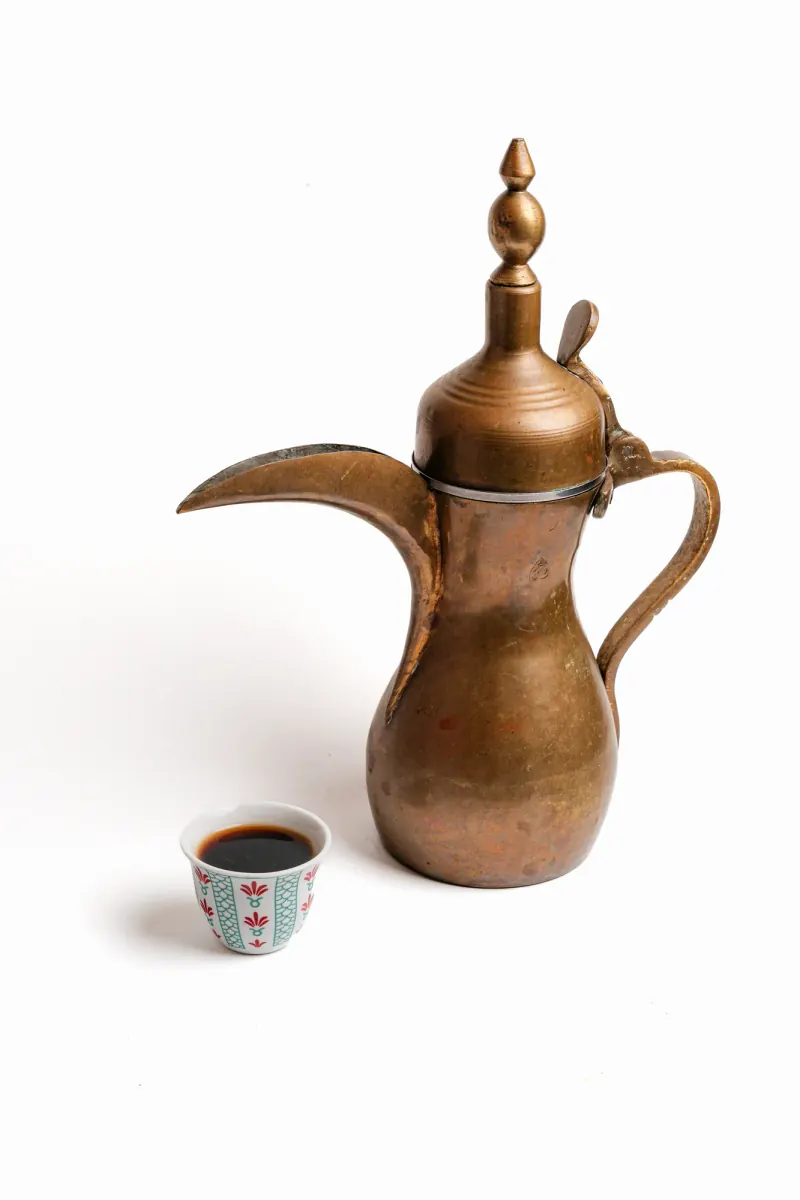 A brass dallah and a small coffee cup